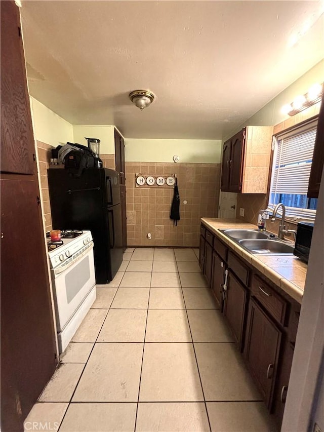 878 E Hawthorne Pl, Pomona, CA 91767 - kitchen featuring dark brown cabinetry, tile walls, white gas stove, a sink, and light tile patterned floors