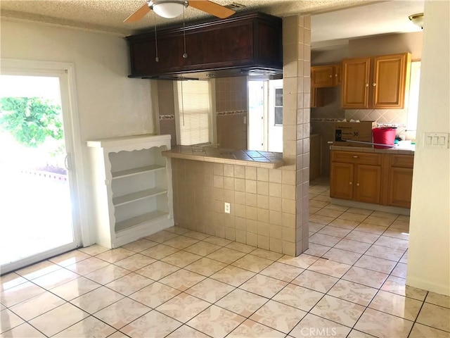 kitchen featuring ceiling fan, tasteful backsplash, tile countertops, a textured ceiling, and light tile patterned floors