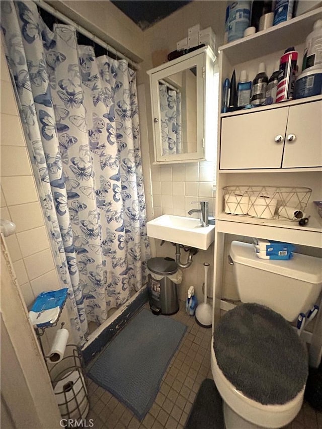 bathroom featuring tasteful backsplash, sink, tile walls, tile patterned flooring, and toilet