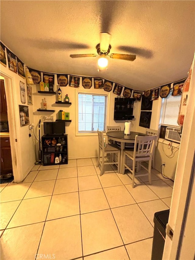 dining area featuring ceiling fan, cooling unit, light tile patterned floors, and a textured ceiling