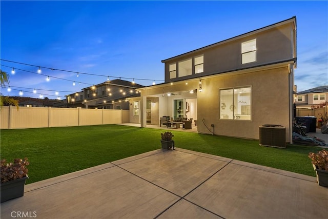 back house at dusk with a patio area, a yard, and central AC unit