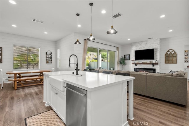 kitchen with stainless steel dishwasher, sink, pendant lighting, a center island with sink, and white cabinetry