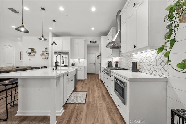 kitchen featuring white cabinetry, light hardwood / wood-style floors, and decorative light fixtures