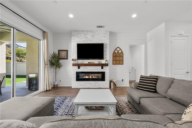 living room featuring dark hardwood / wood-style floors, a large fireplace, and wooden walls