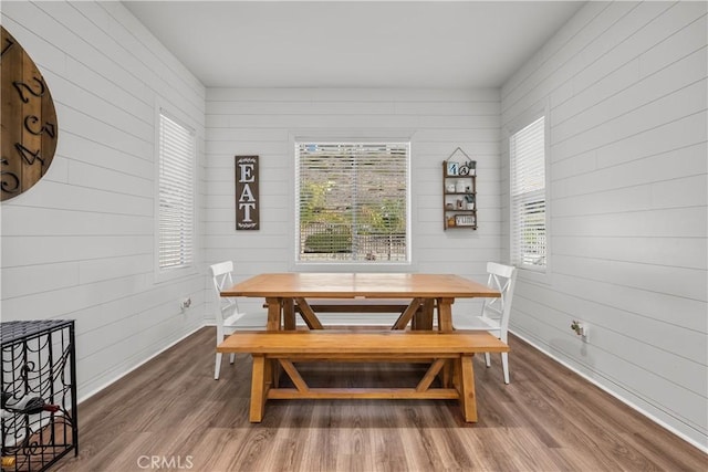 dining room with wood walls and dark wood-type flooring