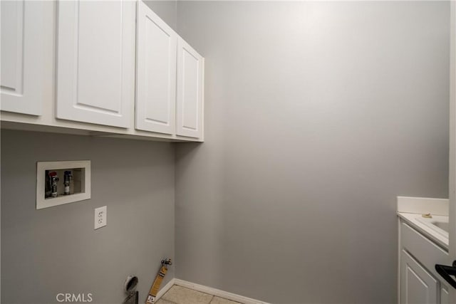 washroom featuring gas dryer hookup, cabinets, light tile patterned floors, and hookup for a washing machine