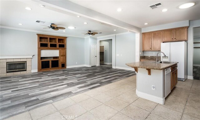 kitchen featuring light stone countertops, ceiling fan, crown molding, light hardwood / wood-style floors, and a breakfast bar area