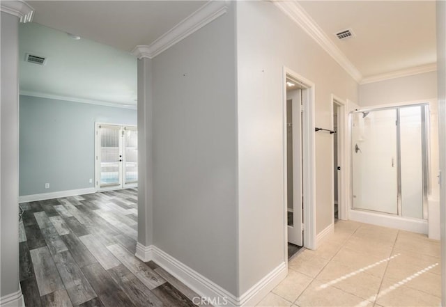 hallway featuring light hardwood / wood-style floors, crown molding, and french doors