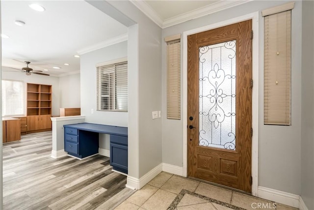 foyer featuring ceiling fan, ornamental molding, built in desk, and light wood-type flooring