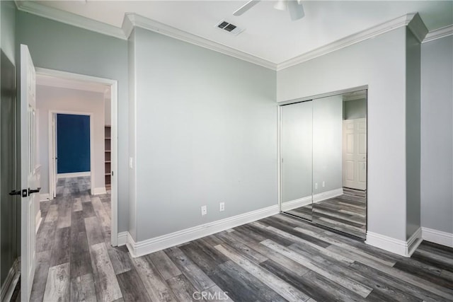 unfurnished bedroom featuring a closet, dark wood-type flooring, ceiling fan, and crown molding