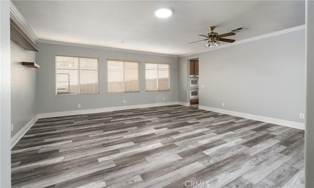 empty room with ornamental molding, a healthy amount of sunlight, and wood-type flooring