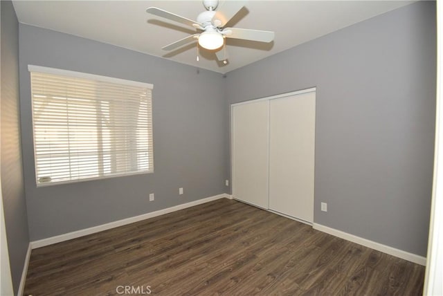 unfurnished bedroom with dark hardwood / wood-style flooring, a closet, and ceiling fan