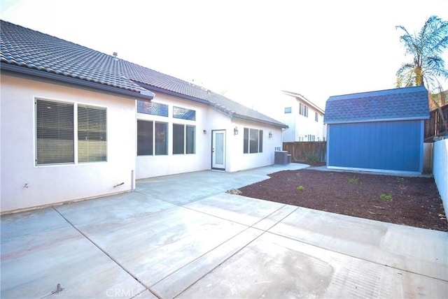 rear view of house featuring a patio area, cooling unit, and a storage shed