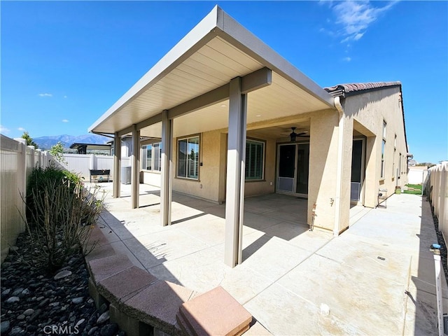 back of house with ceiling fan, a mountain view, and a patio area