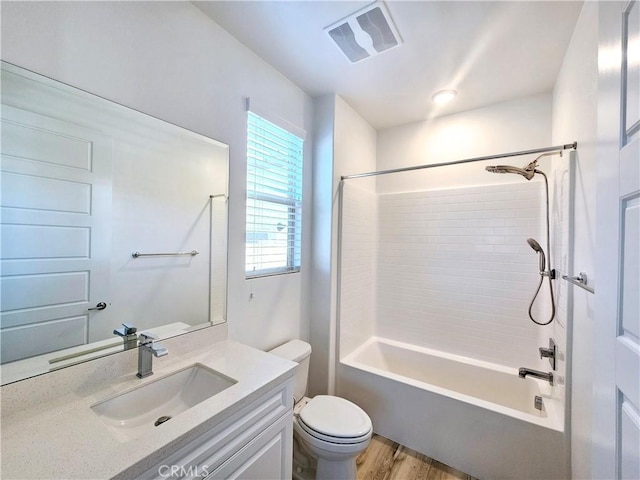 full bathroom featuring vanity, hardwood / wood-style floors, tiled shower / bath combo, and toilet