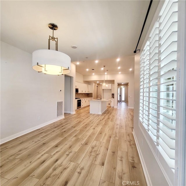 unfurnished living room with sink and light wood-type flooring