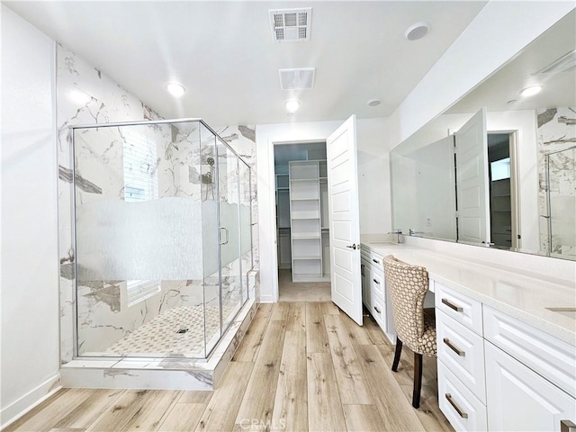 bathroom with walk in shower, vanity, and wood-type flooring