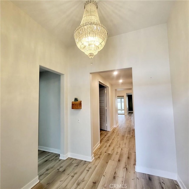 corridor featuring a notable chandelier and light hardwood / wood-style flooring