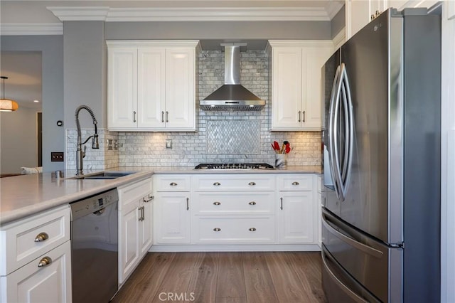 kitchen with wall chimney range hood, decorative backsplash, light wood-type flooring, appliances with stainless steel finishes, and white cabinetry