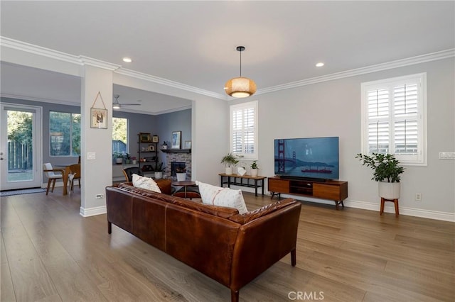 living room featuring a healthy amount of sunlight, crown molding, and light hardwood / wood-style flooring