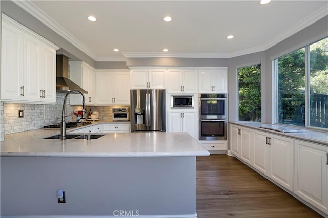 kitchen featuring dark wood-type flooring, white cabinets, wall chimney exhaust hood, ornamental molding, and stainless steel appliances