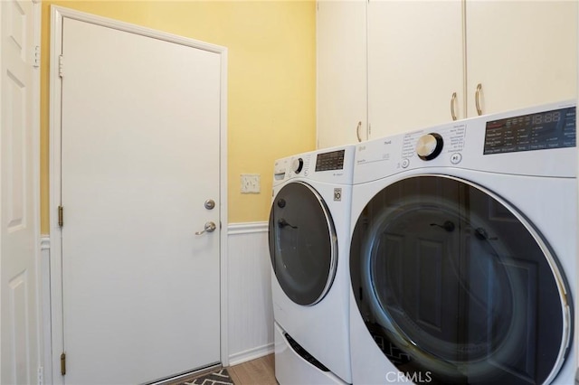 laundry room featuring hardwood / wood-style flooring, washer and dryer, and cabinets