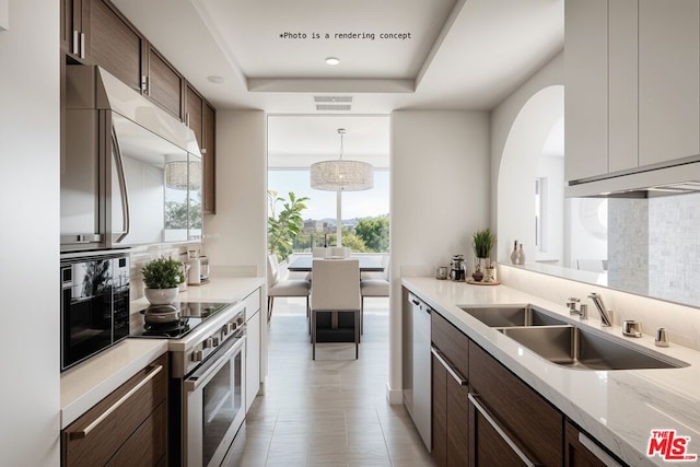 kitchen with a raised ceiling, tasteful backsplash, sink, hanging light fixtures, and stainless steel appliances