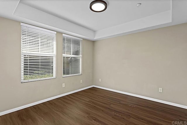 spare room featuring a tray ceiling and dark hardwood / wood-style floors