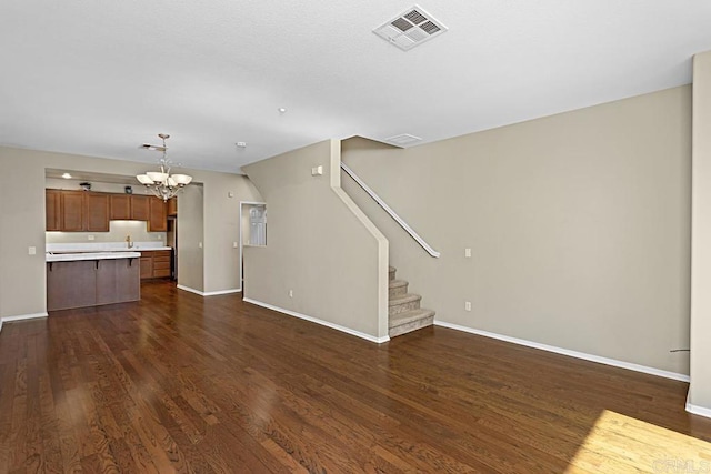 unfurnished living room with a chandelier and dark hardwood / wood-style flooring