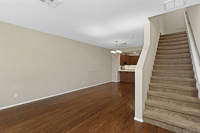 unfurnished living room featuring dark hardwood / wood-style flooring and an inviting chandelier