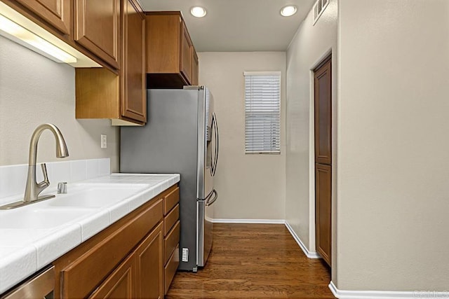 kitchen featuring appliances with stainless steel finishes, tile counters, dark wood-type flooring, and sink