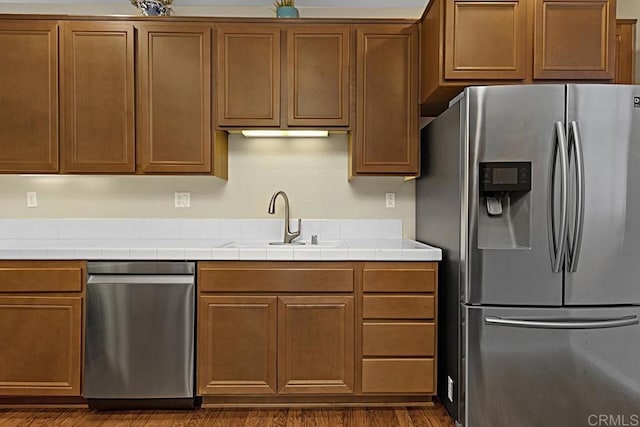 kitchen featuring tile countertops, sink, dark hardwood / wood-style flooring, and appliances with stainless steel finishes