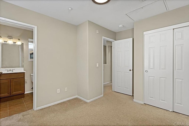 unfurnished bedroom with light colored carpet, sink, and a closet