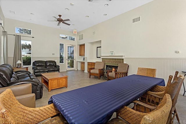 living room with a fireplace, a high ceiling, and ceiling fan