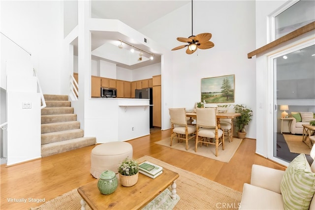 living room with light hardwood / wood-style floors, high vaulted ceiling, and ceiling fan