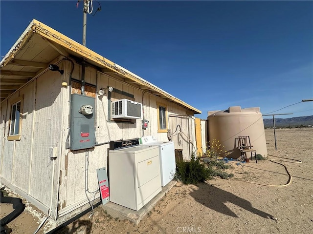 view of side of property featuring washer and clothes dryer and a wall mounted air conditioner