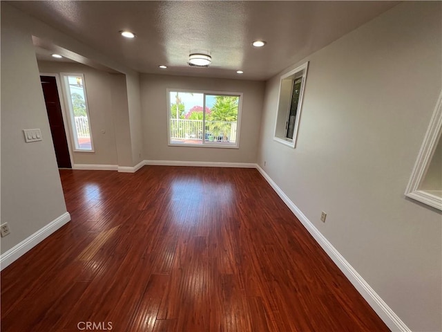 unfurnished room with a textured ceiling and dark wood-type flooring