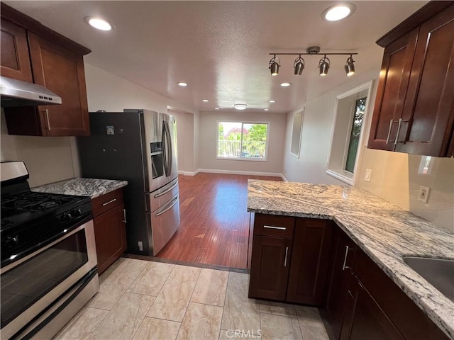 kitchen with sink, light hardwood / wood-style flooring, light stone countertops, kitchen peninsula, and stainless steel appliances