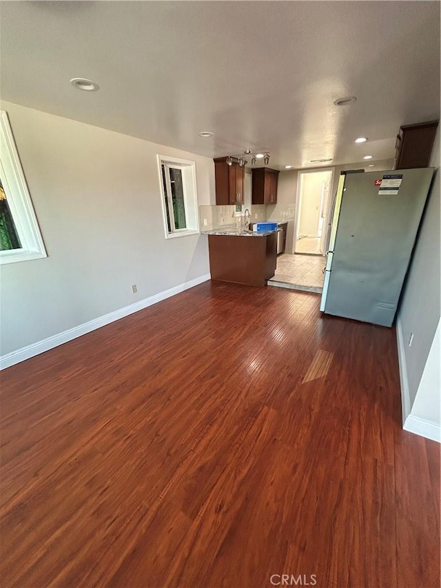 unfurnished living room featuring dark wood-type flooring and sink