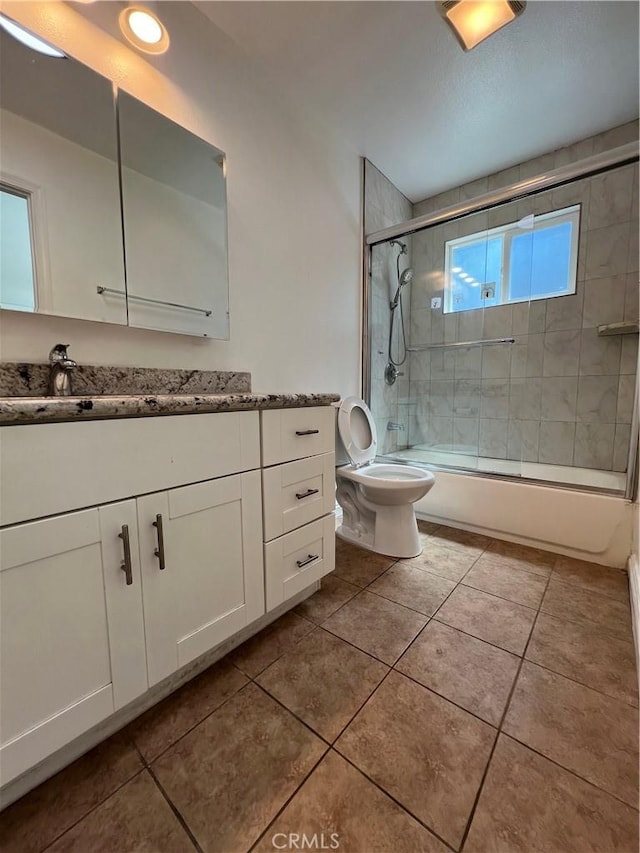 full bathroom featuring tile patterned flooring, vanity, bath / shower combo with glass door, and toilet