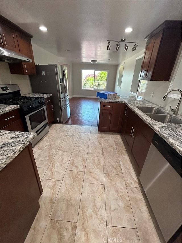 kitchen featuring sink, light stone counters, light hardwood / wood-style flooring, kitchen peninsula, and appliances with stainless steel finishes