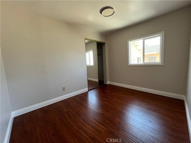 spare room with dark hardwood / wood-style flooring and plenty of natural light