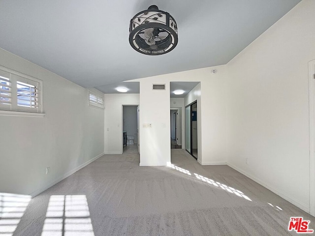 spare room featuring light carpet and lofted ceiling