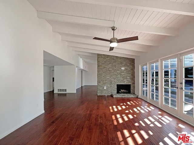 unfurnished living room with french doors, lofted ceiling with beams, a stone fireplace, dark hardwood / wood-style floors, and ceiling fan