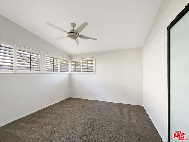 spare room with dark colored carpet, ceiling fan, and vaulted ceiling