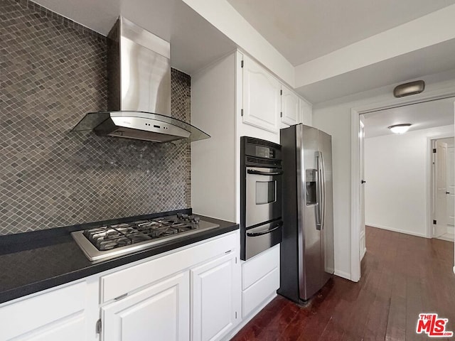 kitchen with white cabinetry, stainless steel appliances, wall chimney range hood, dark hardwood / wood-style flooring, and decorative backsplash