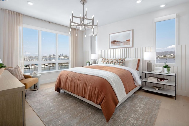 bedroom featuring a chandelier, light wood-type flooring, and multiple windows