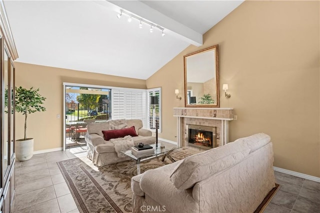 living room featuring track lighting, light tile patterned floors, a tile fireplace, and lofted ceiling with beams