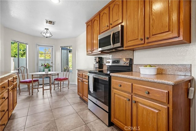 kitchen featuring decorative light fixtures, light tile patterned floors, and appliances with stainless steel finishes