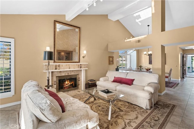 living room with beamed ceiling, an inviting chandelier, high vaulted ceiling, and a tiled fireplace